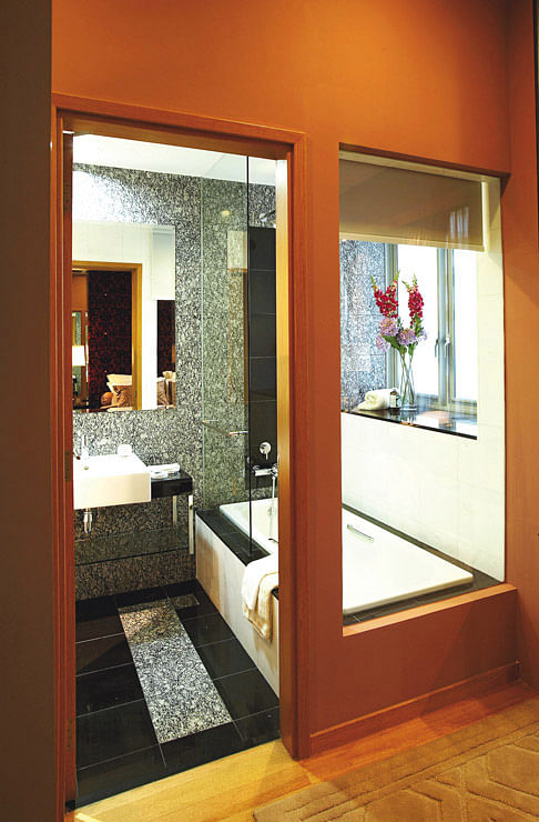 An interior window by the bathtub makes the bathroom appear roomier than it is. The homeowner can pull down the shade for privacy. The master bathroom may be small, but its luxurious, hotel-style finish makes up for the lack of space. Interior design by EJ Square Design