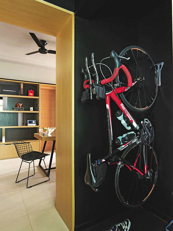 The all-black sports storeroom with wall bicycle mount looks larger than it is as you cannot see where the walls end in this bachelor's modern condominium in Novena.