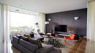 The moody shades of the sunken living room balances out the home's bright and breezy feel.