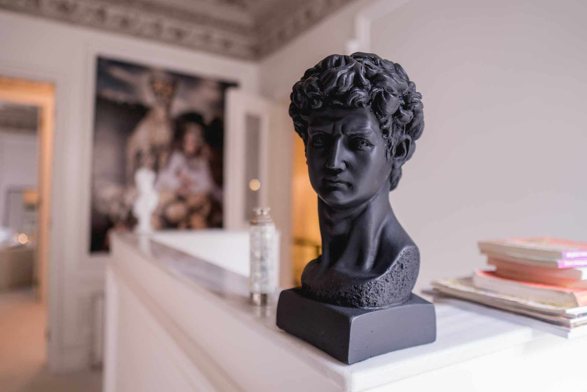 A black bust sculpture of a Grecian man set on a console home bar in an apartment. Photo by Pexels Sami Abdullah