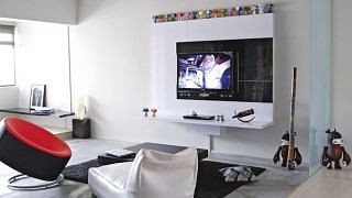 While most TV feature walls are designed to stand out, this one recedes into the white concrete wall, allowing the kooky Mad*l figurines above to steal the spotlight.