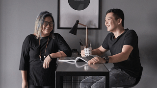 Interior designer couple, Sherlynn Low, and husband Brandon Chen posing at their dining table in their all black 5-room HDB BTO flat in Bukit Batok.