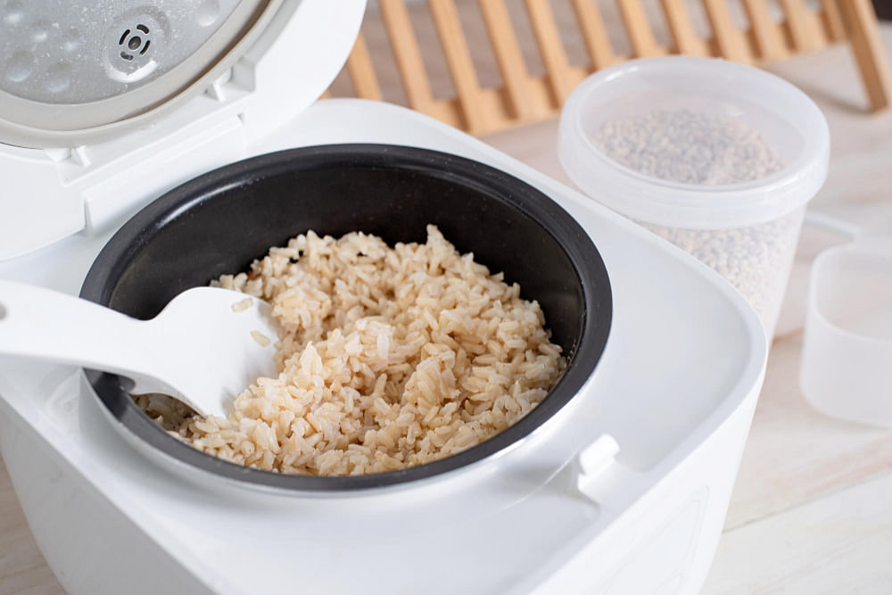 https://media.homeanddecor.com.sg/public/2023/06/opened-electric-rice-cooker-with-cooked-steaming-brown-rice-wooden-countertop-kitchen-1.jpg