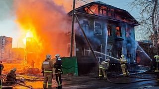 Firefighters extinguish a fire in a two-story wooden house