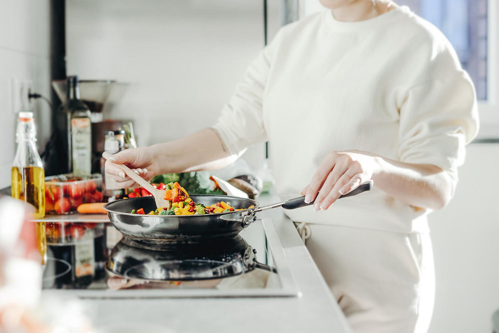 https://media.homeanddecor.com.sg/public/2023/09/woman-cooking-vegetables-pan.jpg